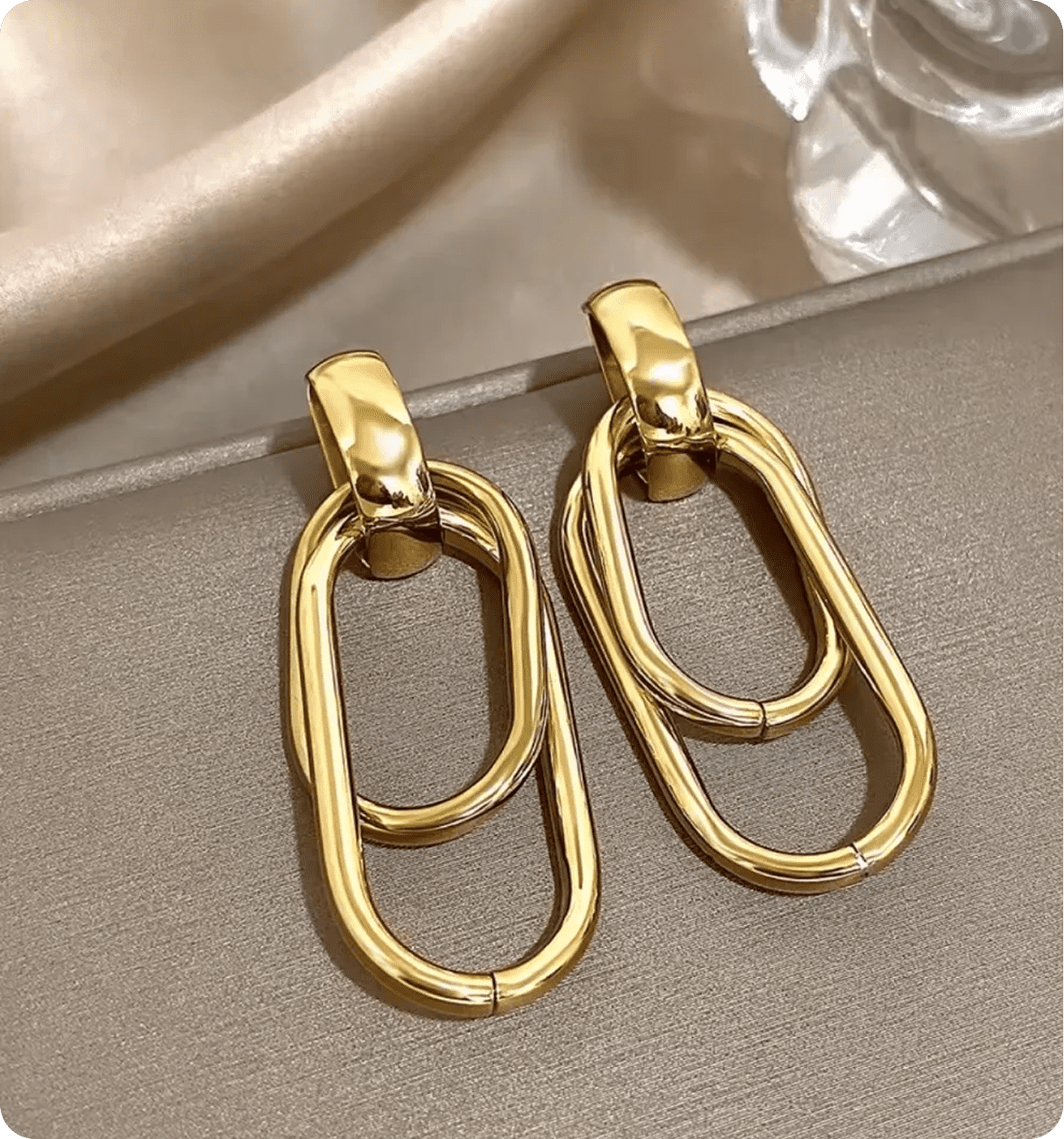Gold chain link earrings on satin fabric